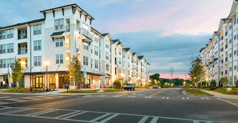 an empty street in front of an apartment building at sunset